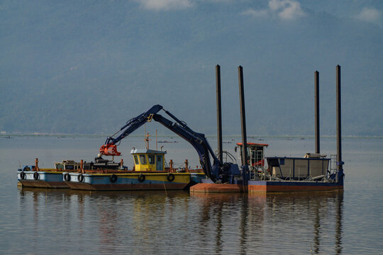 dredger equipped with excavator on the lake to clean from garbage