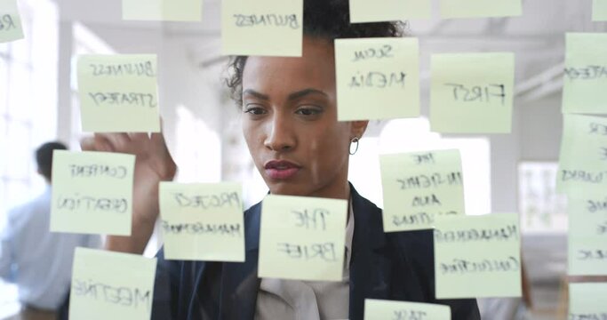 Sticky notes, strategy and black woman planning on glass board in office. Mind map, problem solving and female employee brainstorming, thinking and working on creative marketing ideas in workplace.