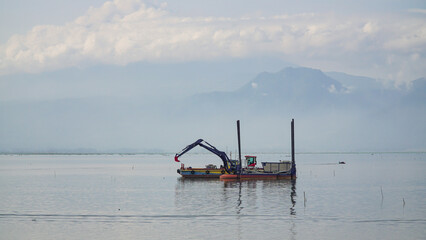 dredger equipped with excavator on the lake to clean from garbage