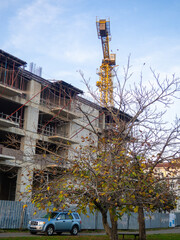 Fototapeta na wymiar Construction crane over an unfinished house. Economic crisis. Stopped building. Concrete walls of the house.