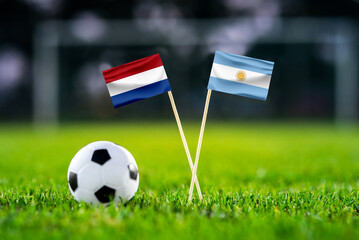 Netherlands - Argentina. Quater-finals football match. Handmade national flags and soccer ball on green grass. Football stadium in background. Black edit space.