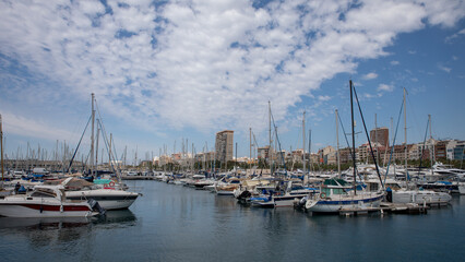 Fototapeta na wymiar Beautiful port of Alicante, Spain at Mediterranean sea. Luxury yachts, ships, ferries and fishing boats sailing and standing in rows in harbor
