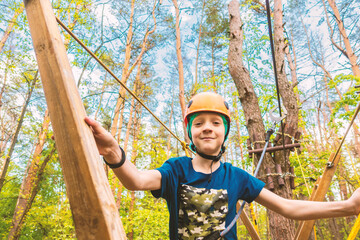 A boy in a helmet on a cable car in the forest overcomes obstacles