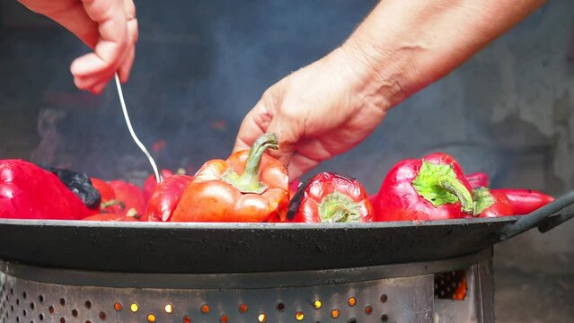 Roasting red peppers for a smoky flavor and quick peeling. Thermal processing of the pepper crop on a metal circle. Brazier container used to burn charcoal fuel for cooking, heating or cultural ritual
