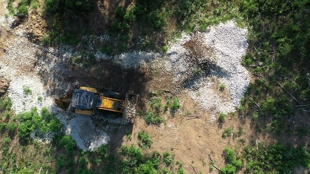 A modern tractor on a construction site from the air. A yellow wheel loader lifts and moves garbage. Heavy machinery is working at the facility.