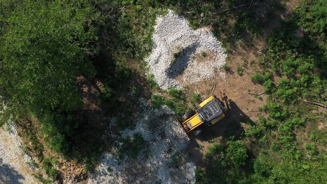 A modern tractor on a construction site from the air. A yellow wheel loader lifts and moves garbage. Heavy machinery is working at the facility.