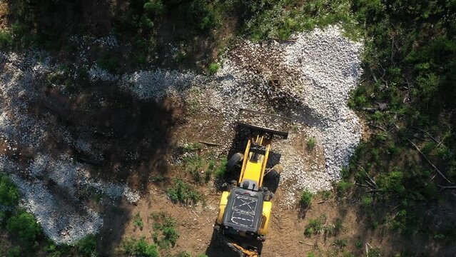 A modern tractor on a construction site from the air. A yellow wheel loader lifts and moves garbage. Heavy machinery is working at the facility.