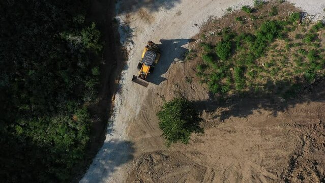 A modern tractor on a construction site from the air. A yellow wheel loader lifts and moves garbage. Heavy machinery is working at the facility.