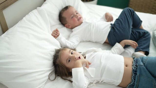 Adorable girl and boy laying on bed playing at bedroom