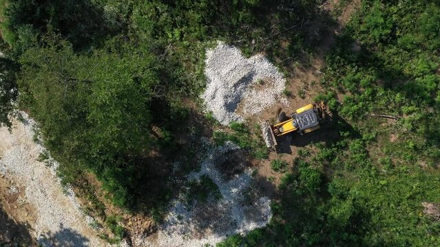 A modern tractor on a construction site from the air. A yellow wheel loader lifts and moves garbage. Heavy machinery is working at the facility.
