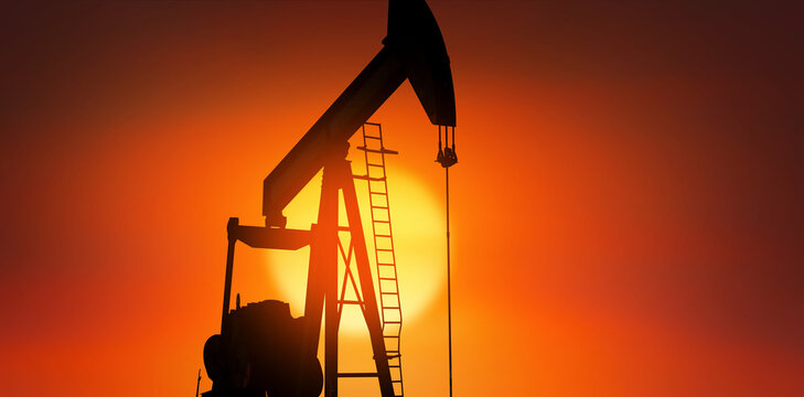Silhouette of an oil well in operation at sunset.