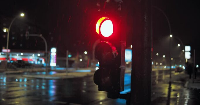 Ein Ampel leuchtet rot an einer Kreuzung beim Schnee