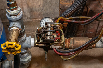 Well water pump pressure switch and plumbing pipes. Home repair, maintenance and renovation concept