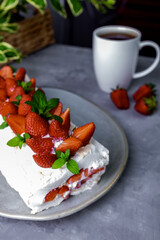 Meringue roll with strawberries and curd cream. Dessert decorated with berries and mint leaves. Homemade baking.