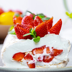 Meringue roll with strawberries. A piece of roll decorated with berries, on a white plate, close-up. summer dessert