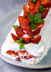 Meringue roll with strawberries and curd cream. Dessert decorated with berries and mint leaves. Homemade baking.