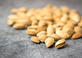 shelled almonds on a dark stone table with a wooden spoon and a bowl. Almonds in a wooden bowl.