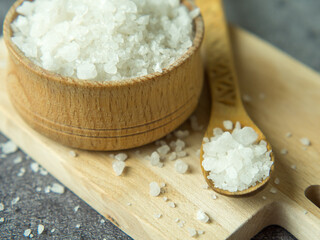sea crystal salt in a wooden bowl and spoon on a wooden board