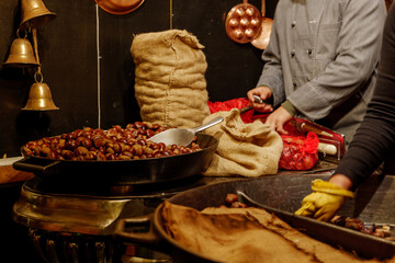 Close up night view at heap of roasted chestnuts on hot pan at stall in Christmas Market in Germany.