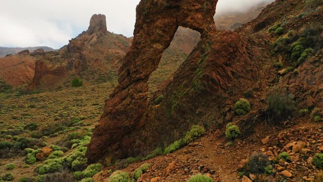 Natural volcanic formation rock with hole Queen Shoe Teide National Park Tenerife Spain. Barren lifeless mountains. Deserted hiking area. Canary Island. Cinematic flying around the cliff.