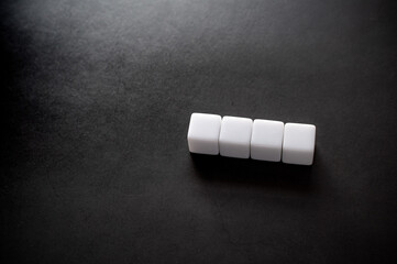 Four white cubes are placed on a black background. Material for composing text.