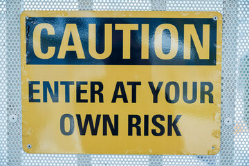 Caution Enter at Your Own Risk on a yellow sign- Miami, Florida