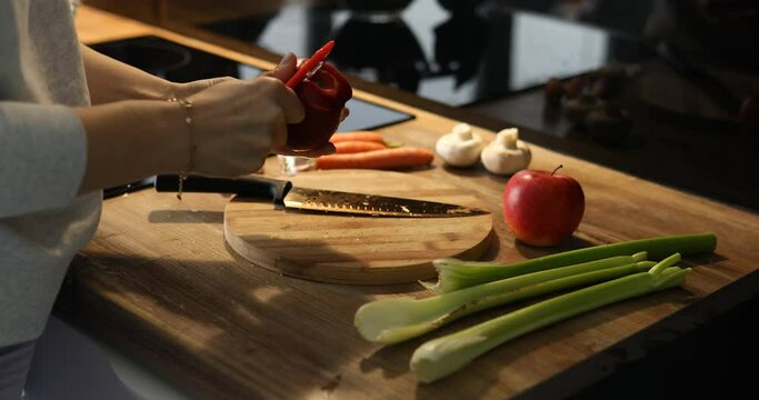 Unrecognizable cropped woman professionally skillfully peel fresh red apples in kitchen corner. Cook healthy fruit salad