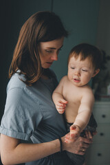 mom holds a one-year-old baby in her arms, 