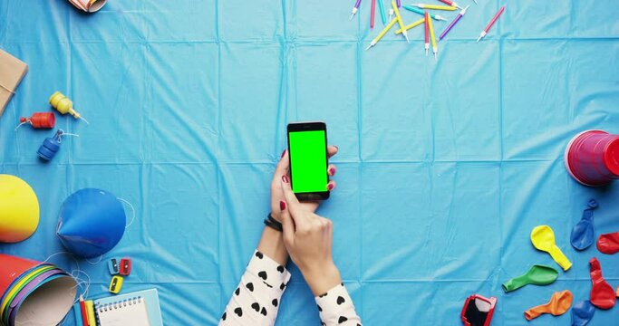 Party, hand and green screen phone scrolling of an event planner searching social media online. Fun, blue background and hands of a woman browsing the internet with a green blank screen