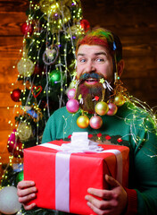 Merry Christmas and happy new year. Smiling man with decorated beard holds gift box. Winter holiday.