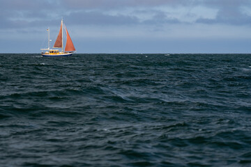 Fototapeta premium Lonely Sailing boat on blue open sea. Concept of loneliness, solitude and desolation