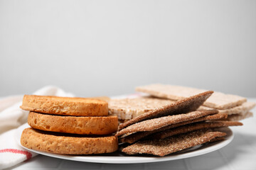 Fototapeta na wymiar Plate of rye crispbreads, rice cakes and rusks on white table, space for text