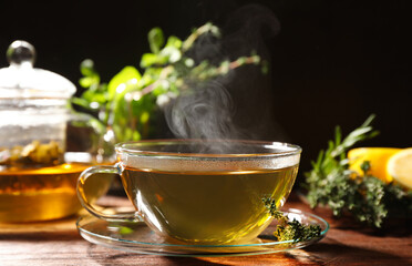 Cup of aromatic herbal tea and thyme on wooden table