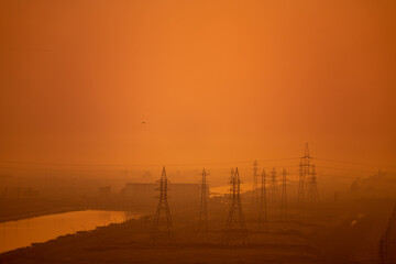 Fototapeta premium High voltage power lines and transmission towers at golden sunset. Industry energy supply concept
