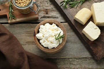 Delicious tofu cheese with rosemary and soy beans on wooden table, flat lay