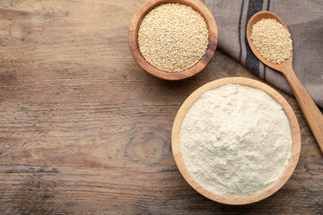 Quinoa flour in bowl and spoon with seeds on wooden table, flat lay. Space for text