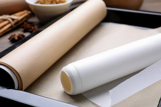 Rolls of parchment paper in baking pan on table, closeup