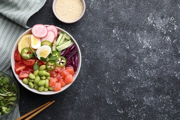 Poke bowl with salmon, edamame beans and vegetables on black table, flat lay. Space for text