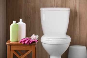 Cleaning supplies on stool near toilet bowl indoors, space for text