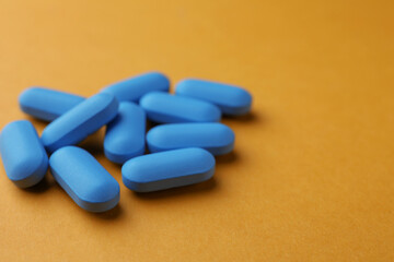 Pills on orange background, space for text. Potency problem