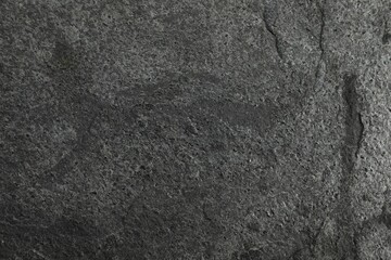 Texture of dark grey stone surface as background, closeup