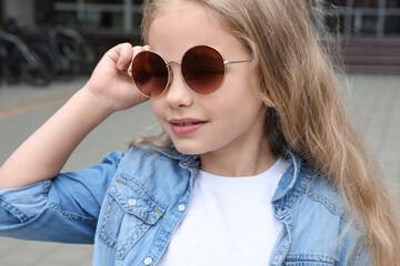 Girl wearing stylish sunglasses on street near building