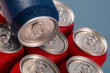 Cold red soda cans with a blue one for conceptual use