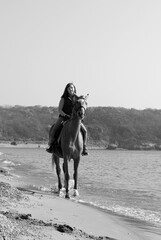 Fototapeta na wymiar Girl and horse. Horse riding by the sea.