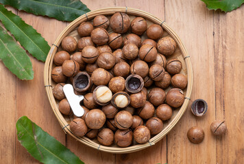 Macadamia nuts with leaf and Macadamia with hard shell on wooden background.