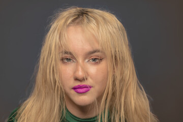 Naklejka premium Young blond LA citizen poses in studio wearing a green leotard and jeans.