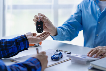 Selling a car. Management concept. The dealer gives the car keys to the new owner or renter with a...