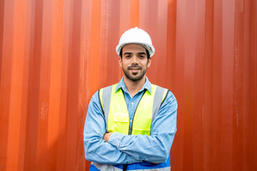 Portrait of confident young hispanic male engineer with container background.