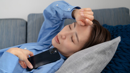 スマートフォンを持ちながら寝てしまう女性