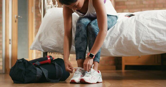 Woman, tie shoes and legs in bedroom for fitness training, sports ready and runner exercise. Workout motivation, start cardio performance and healthy lifestyle wellness with bag in morning at home